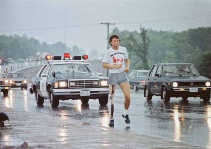 Terry Fox during the Marathon of Hope with an OPP officer tailing behind the young athlete,